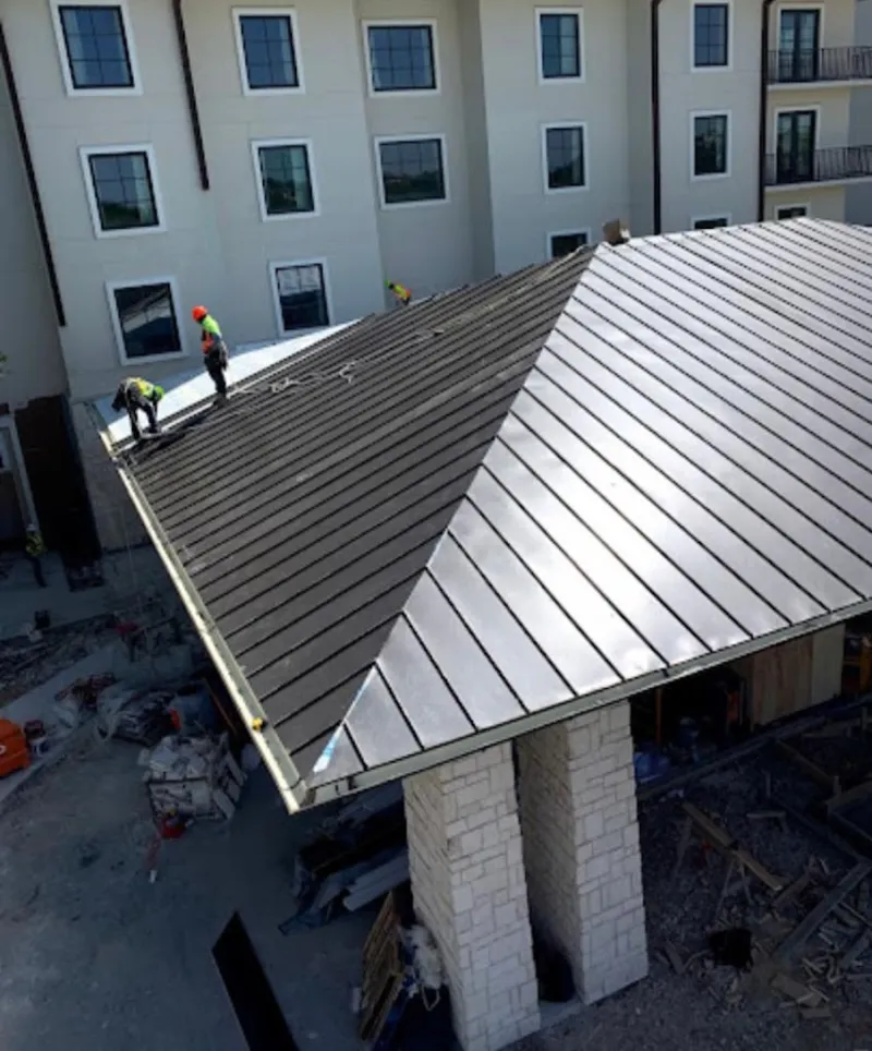 Crew installing standing seam metal roof panels on a commercial project in Belvedere